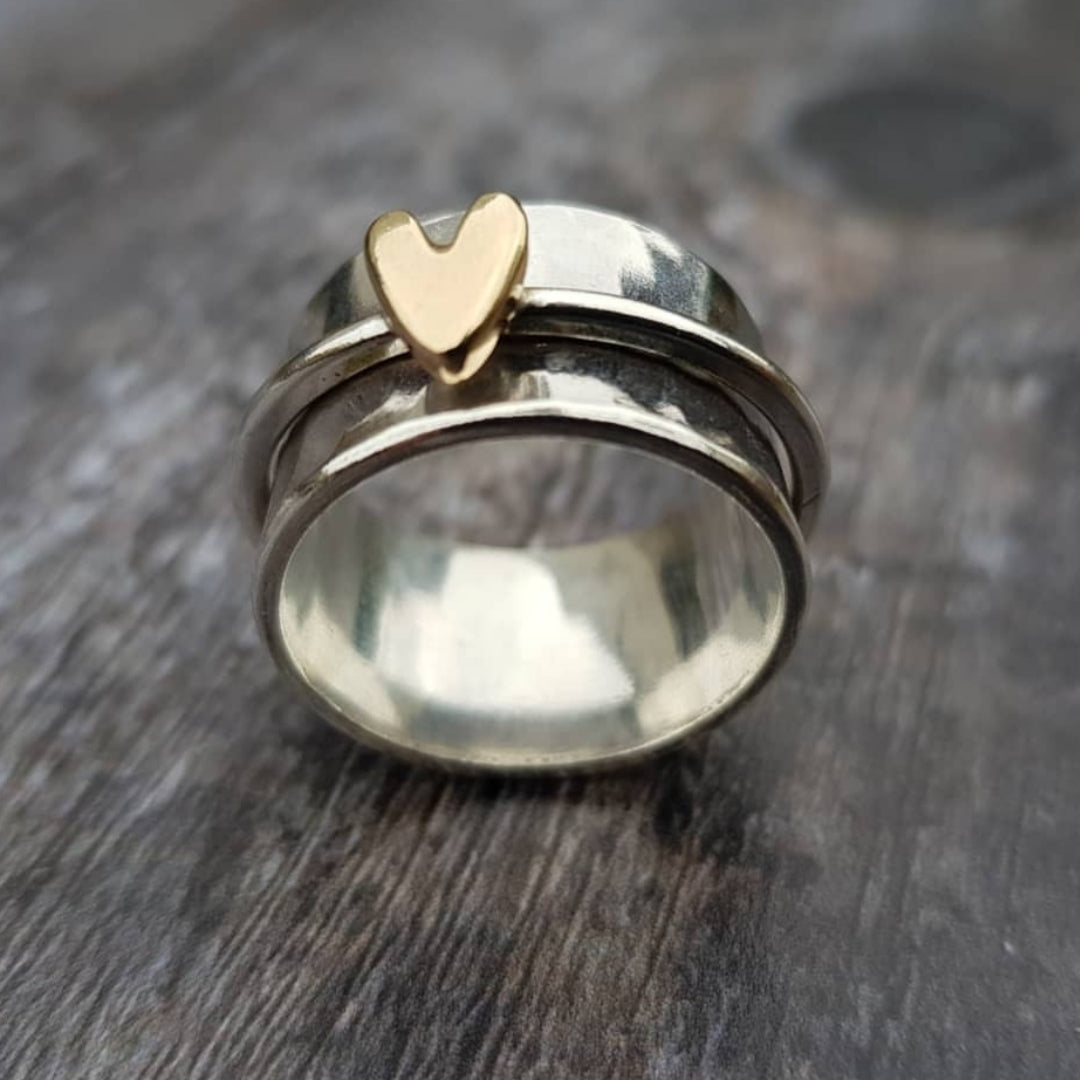 Silver ring with a gold heart on a wooden surface